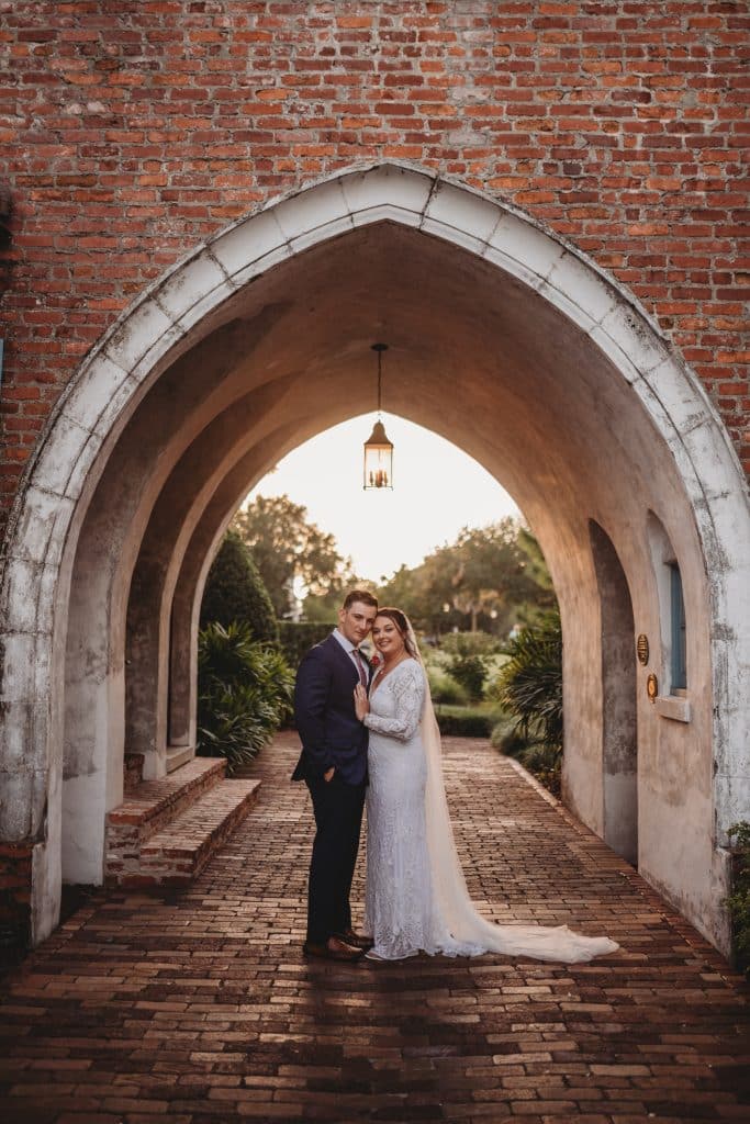 Wedding couple posing under a brick lined arch within a building, near sunset, Ashley Krug Photography, Central FL
