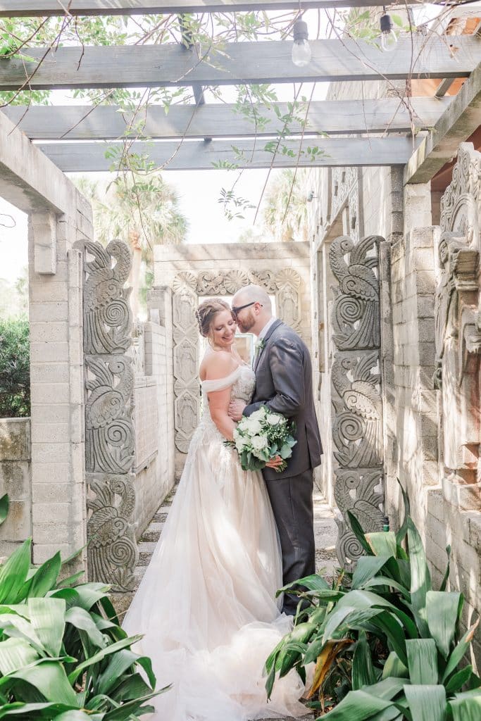Bride and Groom sharing a kiss under a pergola in a garden, outdoors, Central FL