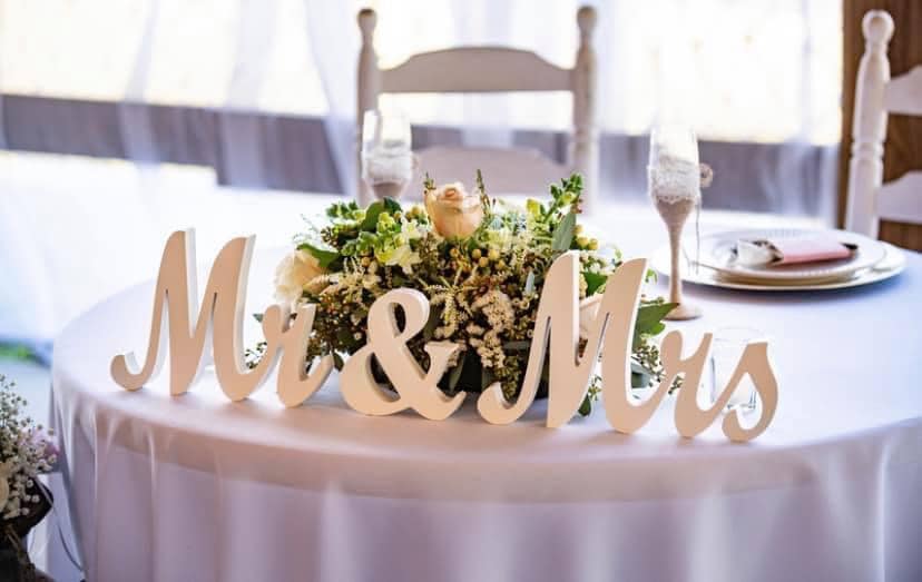 Head table for the wedding couple, Mr & Mrs letters on the table, in front of a small floral display, white tablecloth, white wooden chairs, Orlando, FL