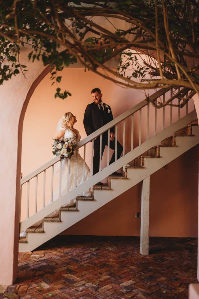 Wedding Couple heading up a staircase to the honeymoon suite, the groom is leading the bride as they look into each other's eyes, Ashley Krug Photography, Central FL