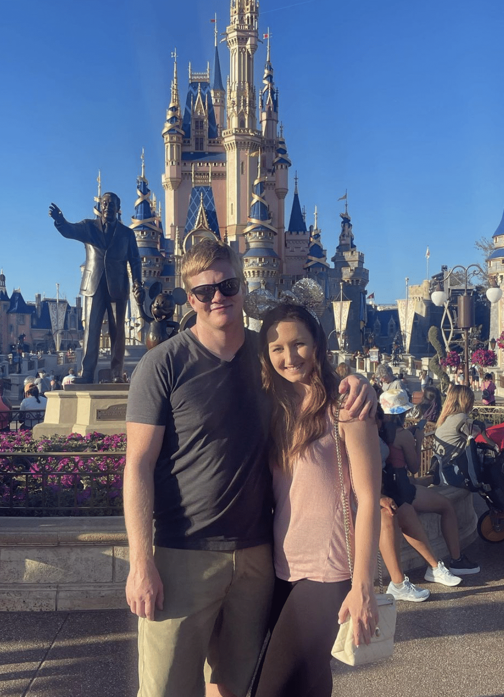 young couple stands in front of castle at Disney world