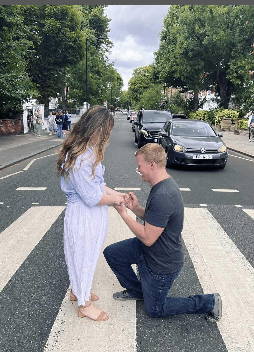 man kneels on famous abbey road proposing to woman