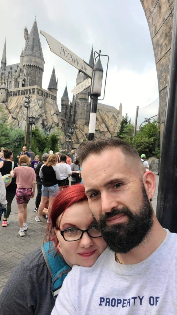 couple poses for selfie together in front of harry potter castle in universal resorts