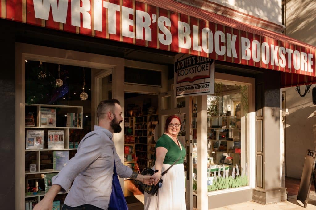 couple walks in front of bookstore holding hands