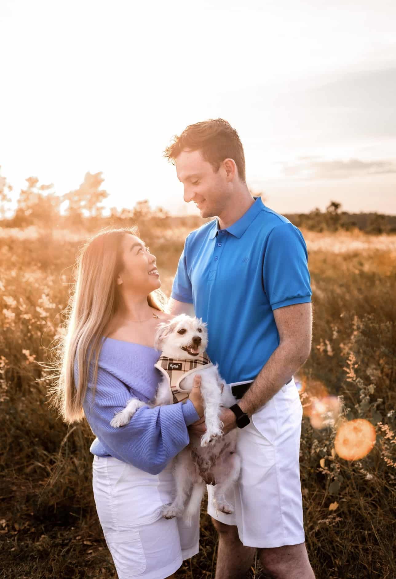 couple pose together for picture holding their dog