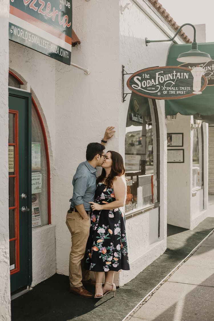 couple stand together in doorway kissing for picture