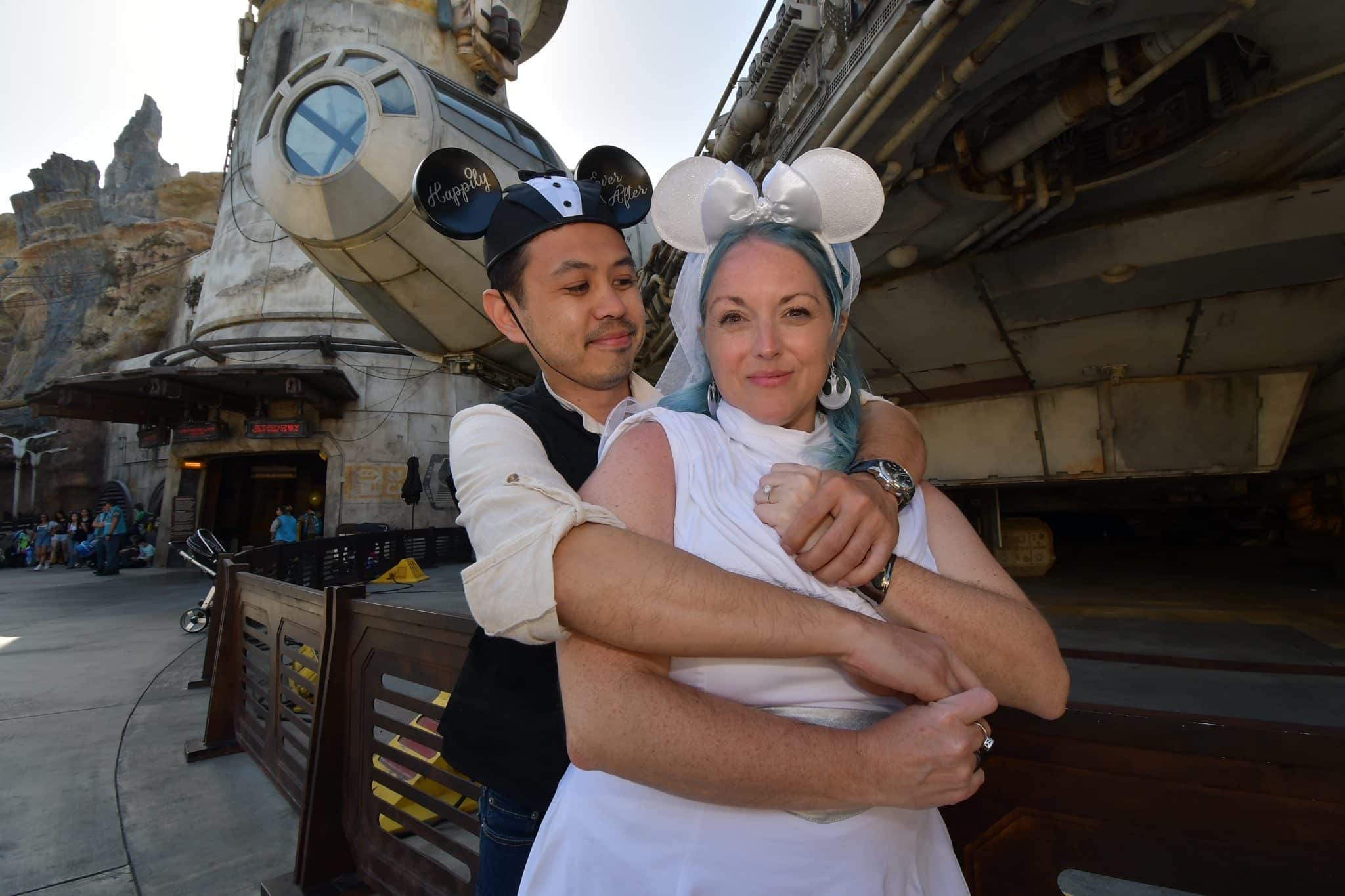 couple pose together wearing bride and groom mickey ears in star wars marriage proposal