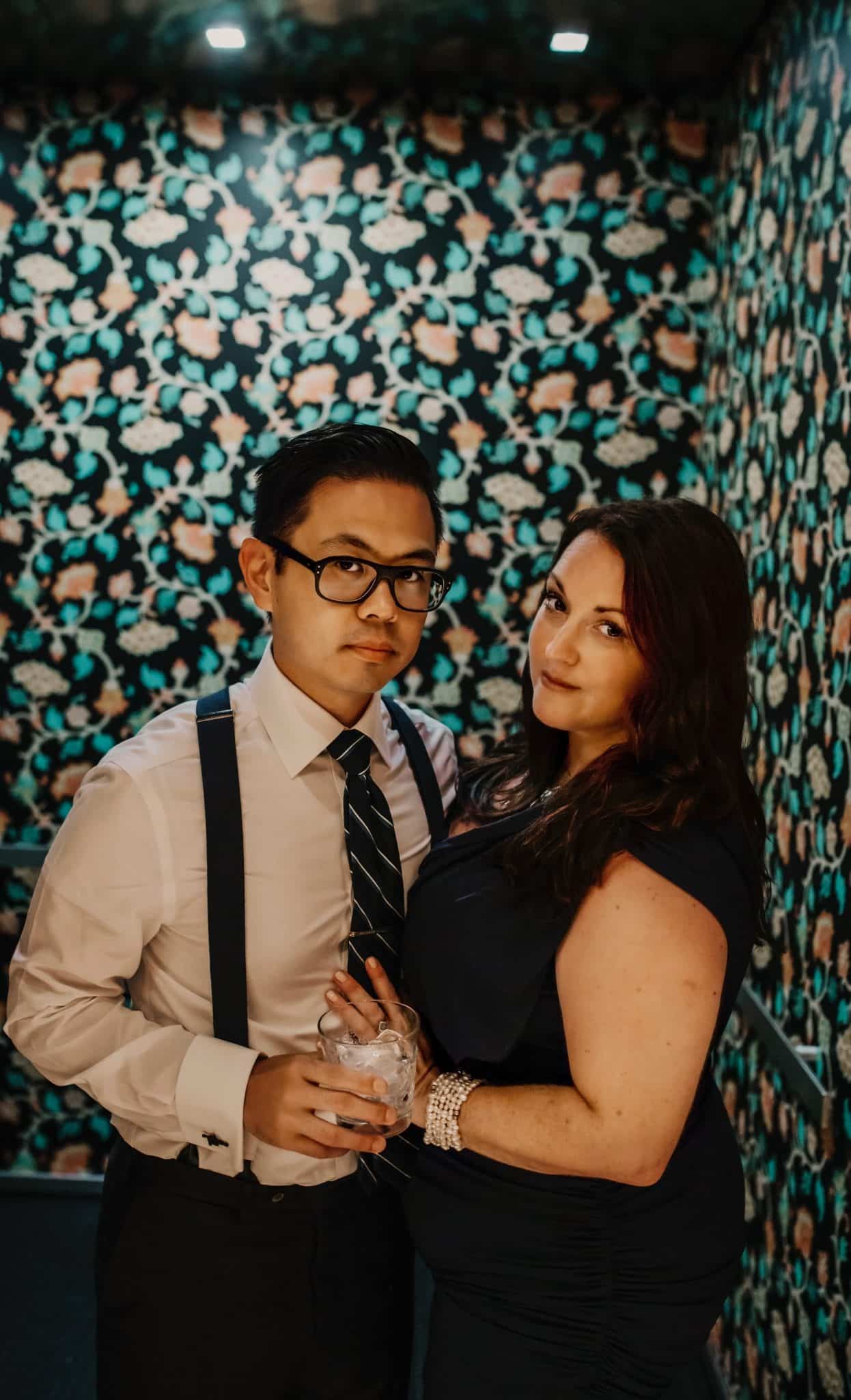 couple stand together in front of walls with patterned paper for picture