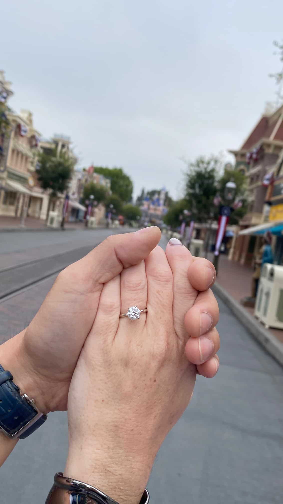 close up picture of two hands holding with engagement ring