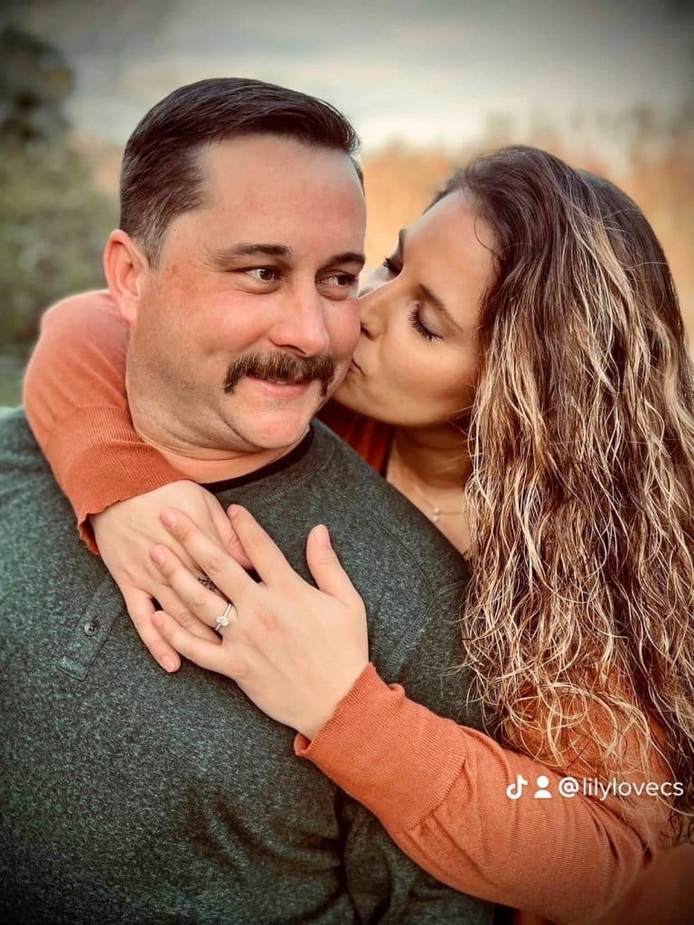 man and woman pose for professional couple portraits together wearing fall colors