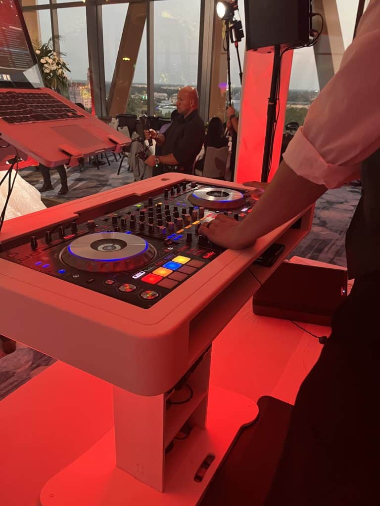 DJ turntable set up on stage at an event, large windows in the background, red uplighting, Orlando, FL