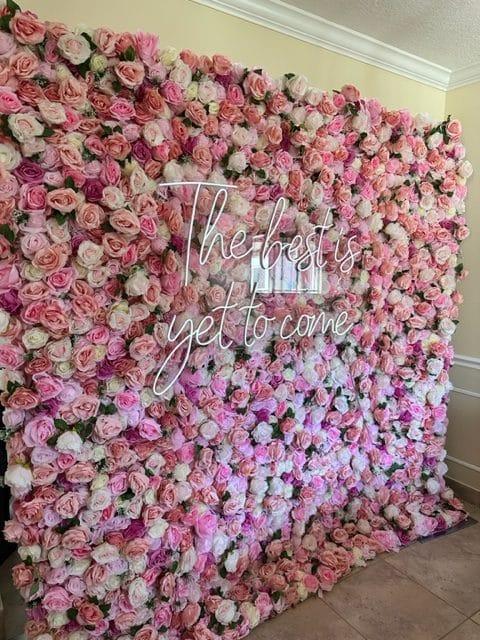 photo booth backdrop of pink and white flowers with a sign that says 