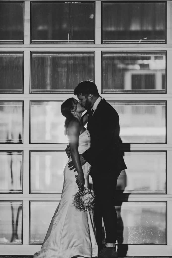 Black and white photo of bride and groom kissing in front of the all glass garage door at Lavender on the Lake, Orlando, FL