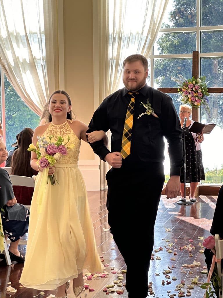 A bridesmaid in a yellow dress and groomsman in a black suit with a yellow tie, walking out at the reception, Diamond Dj Events, Orlando, FL