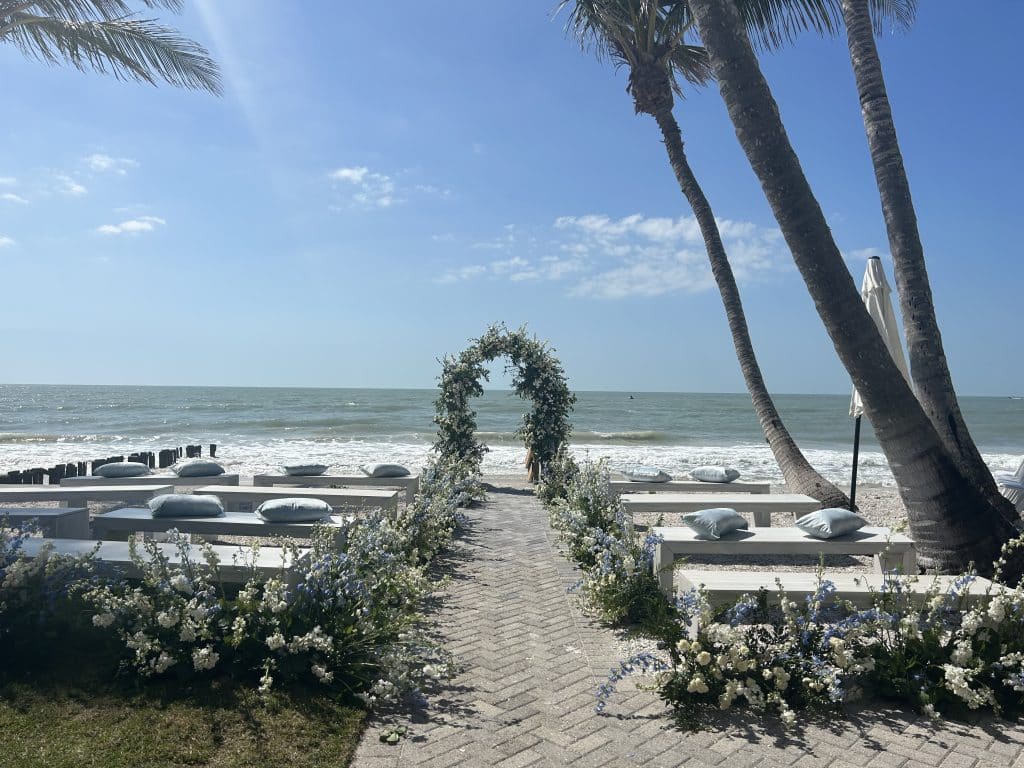 Outdoor wedding ceremony, set beachside with an alter set at the front and benches adorned with cushions, Orlando, FL