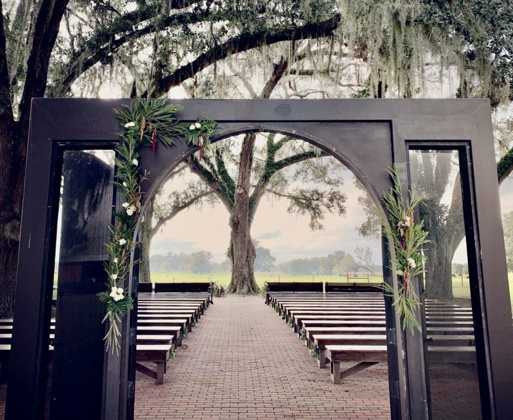 Outdoor ceremony set up, looking at it form inside the venue, audience seats are long wooden benches in rows with a center aisle, Orlando, FL
