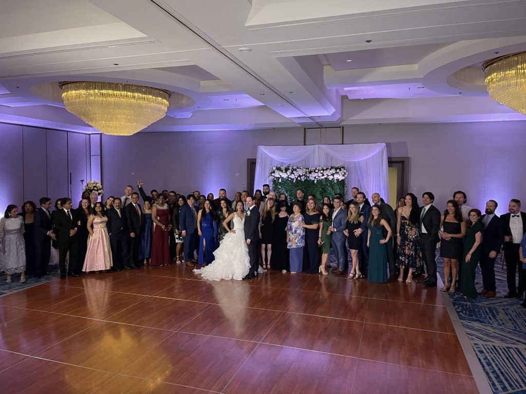 the bride and groom pose on the dance floor for a large group photo with their family and friends, Dash of Class Platinum, Orlando, FL
