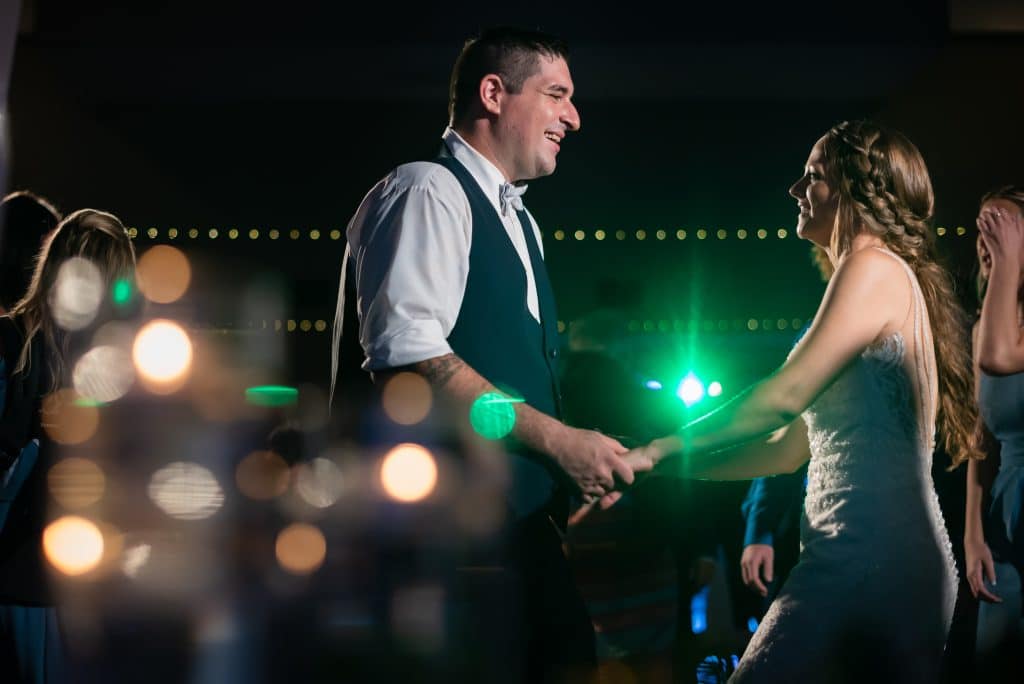 A couple dances at a wedding reception, outdoors, with various lights reflecting in the foreground and background, Diamond Dj Events, Orlando, FL