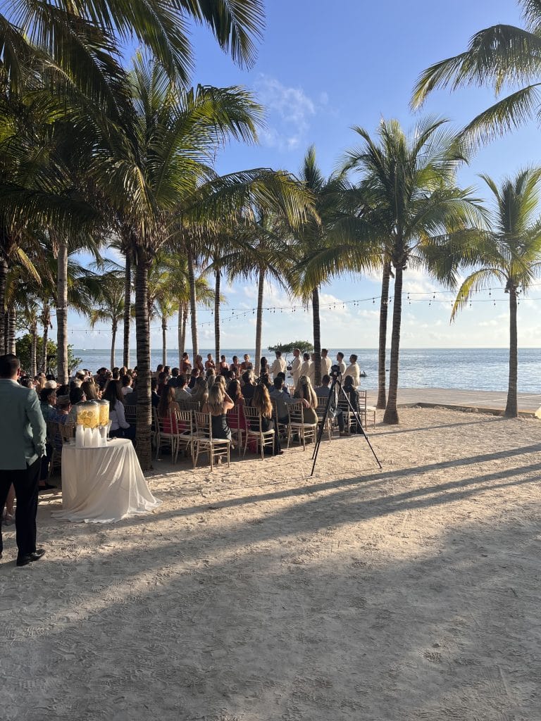 Outdoor wedding ceremony on the beach, on the water, under palm trees, chairs set up to face the water, Dash of Class Platinum, Orlando, FL