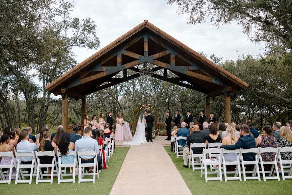Ceremony located outdoors, white chairs in rows with a center aisle, wooden frame pavilion for the ceremony, Serenity Events, Orlando, FL