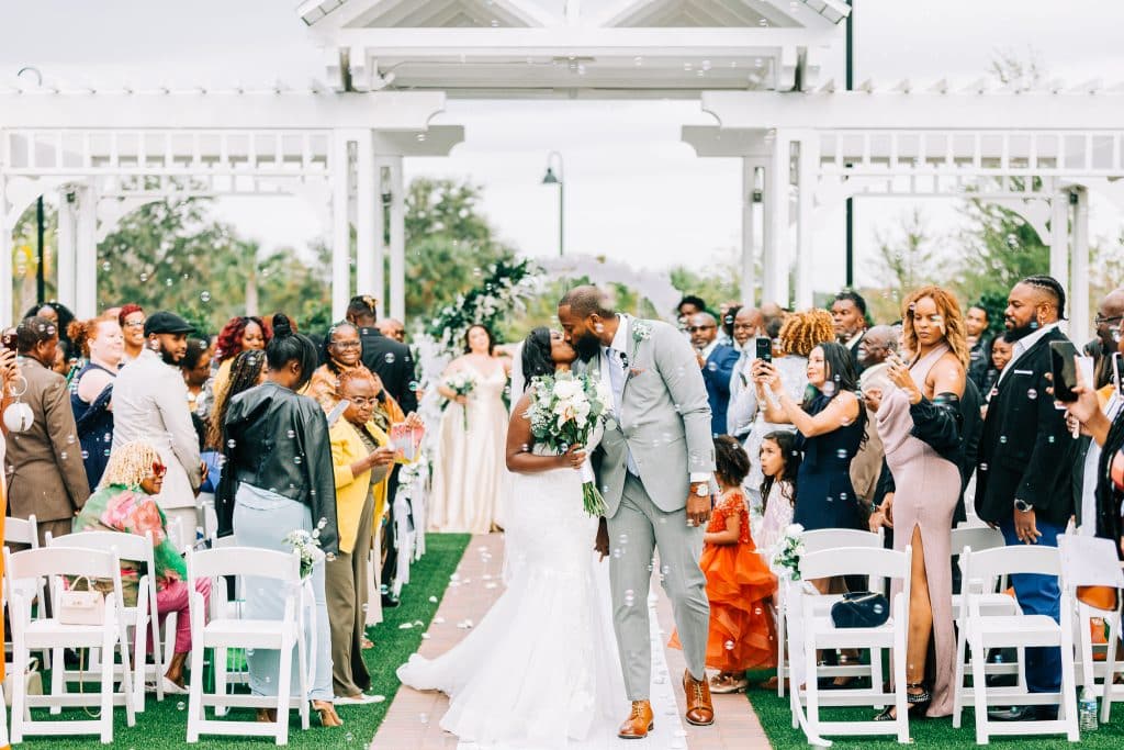 Wedding Couple, man and woman of color, after their ceremony, kissing to celebrate, guests watching and congratulating the couple, Serenity Events, Orlando, FL