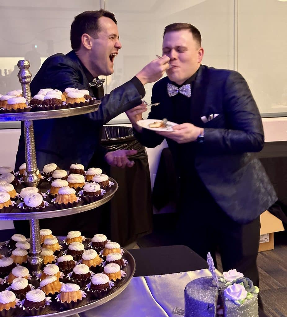 Grooms are feeding each other wedding cupcakes at the dessert table, Diamond Dj Events, Orlando, FL