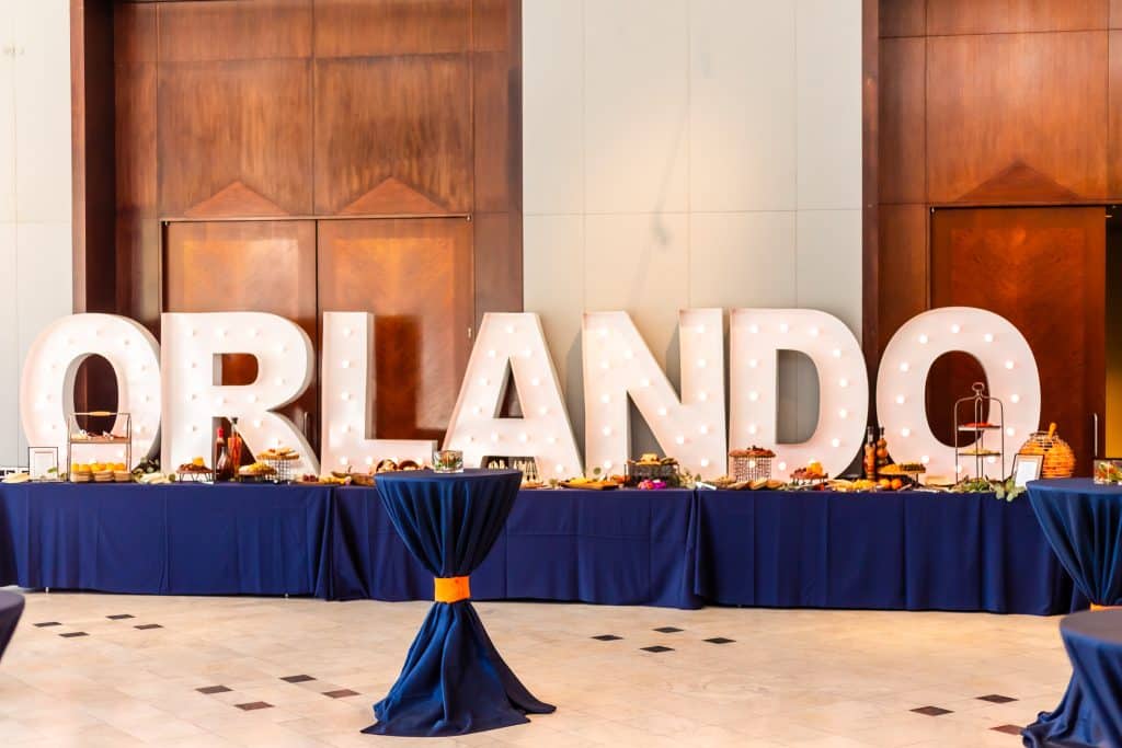 The word ORLANDO spelled out in lighted letter signs, on a buffet table with a blue table cloth, Central FL
