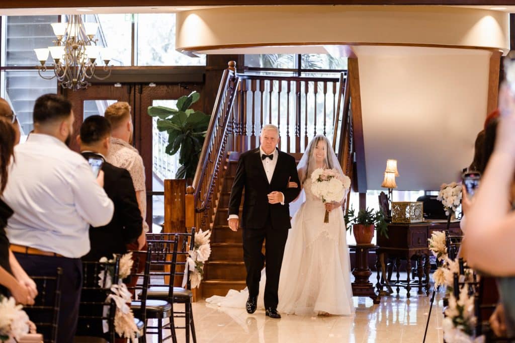 bride and father walk down the aisle at indoor wedding