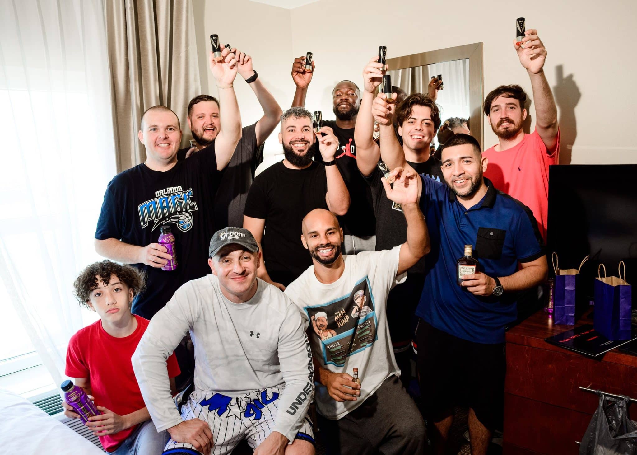 men sitting and standing in room holding shot glasses up smiling