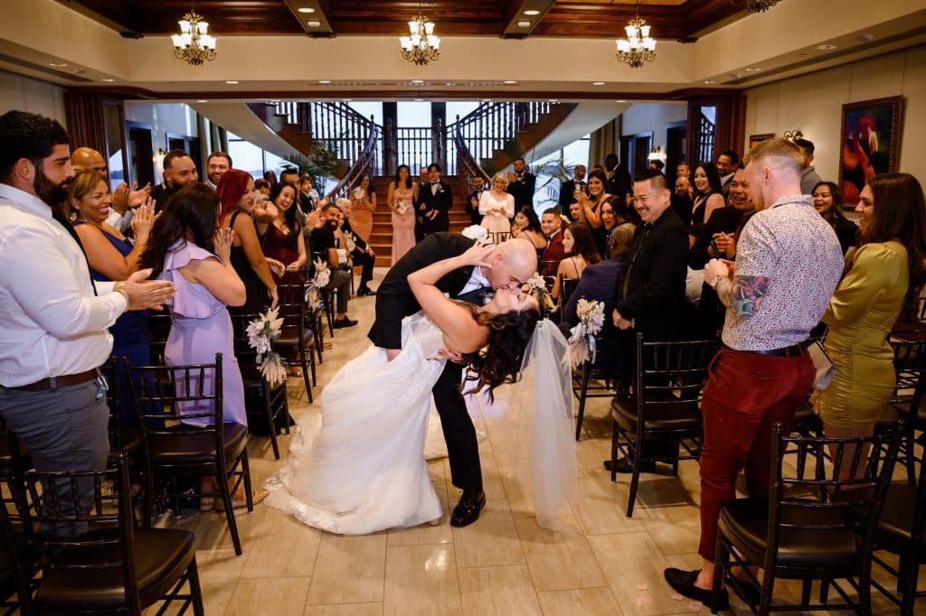 groom dips bride in kiss at the end of aisle after being married
