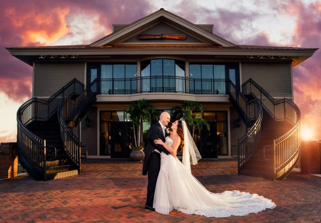 bride and groom pose for picture in front of wedding venue tavares pavilion on the lake