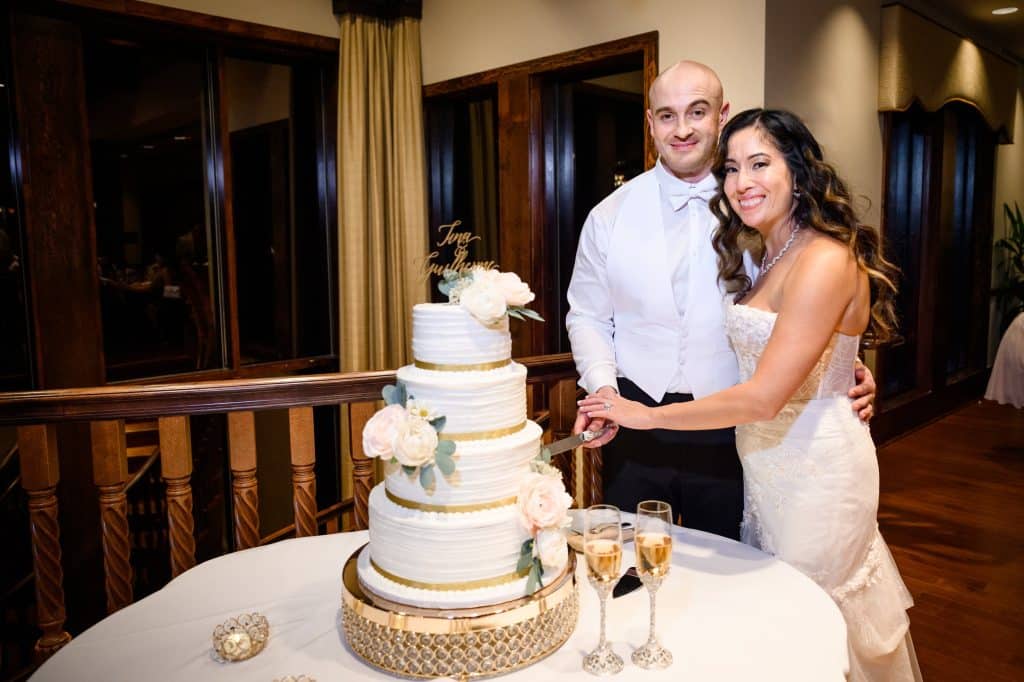 bride and groom pose cutting cake on wedding day