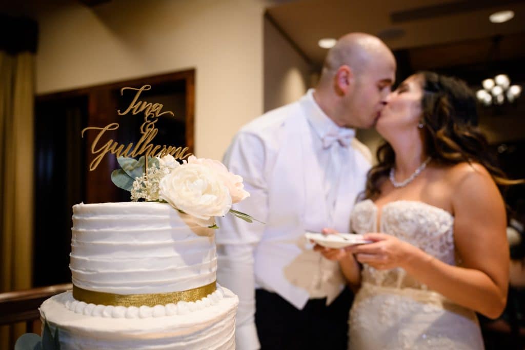 bride and groom kiss after cutting their wedding cake
