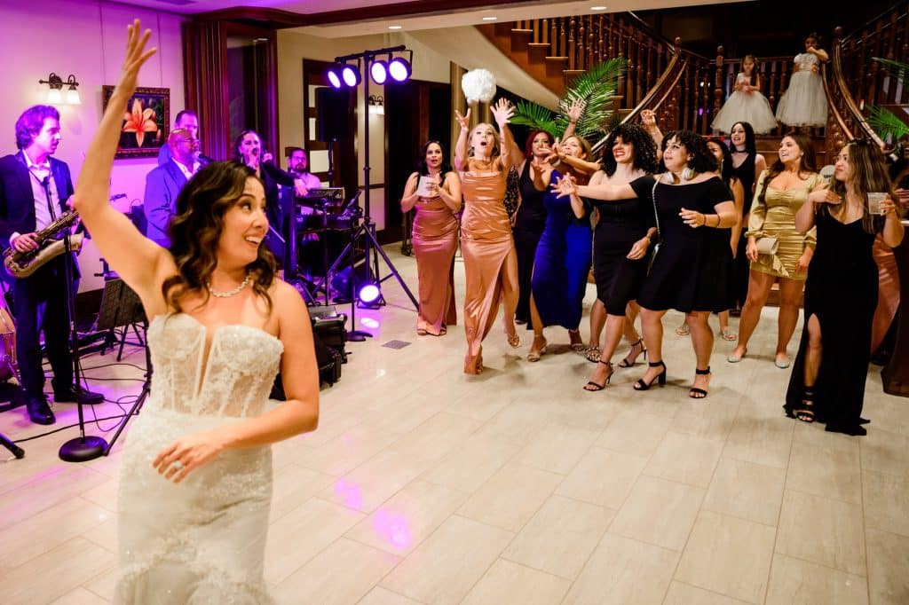bride tosses wedding bouquet to single ladies during wedding reception