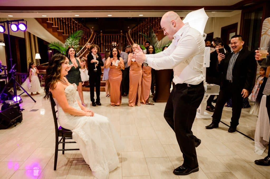 bride sits in front of groom about to take the garter off