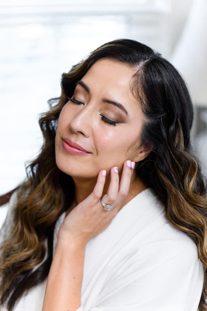 woman pictured with eyes clsoed softly smiling with hand resting on chin
