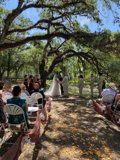 Outdoor wedding ceremony under trees, wedding party at the front with the bride and groom, Orlando, FL