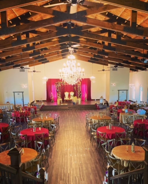 barn venue, wood floors, red tablecloths, round tables, wooden rafters, large chandelier in the center, Orlando, FL