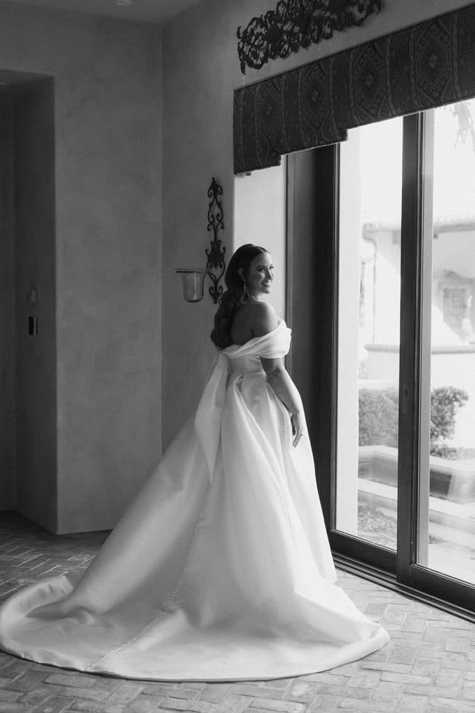Bride standing in the ceiling length window looking outside as she waits for her wedding, Central FL