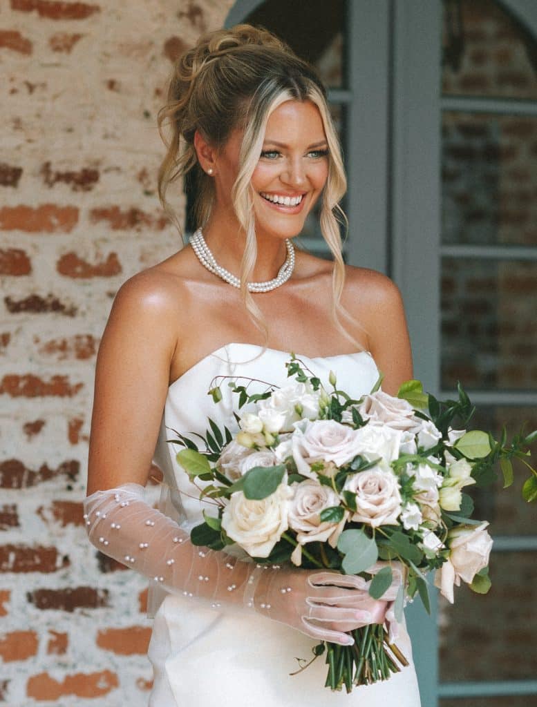 Close up of a bride holding her beautiful bouquet of white and pink roses, brick wall in the background, Central FL