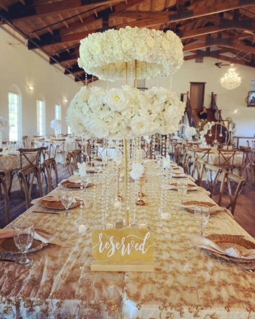 tables cape of gold tablecloth, gold chargers, clear stemware, reserved sign, votive candles, white flowers in a tall centerpiece, Orlando, FL