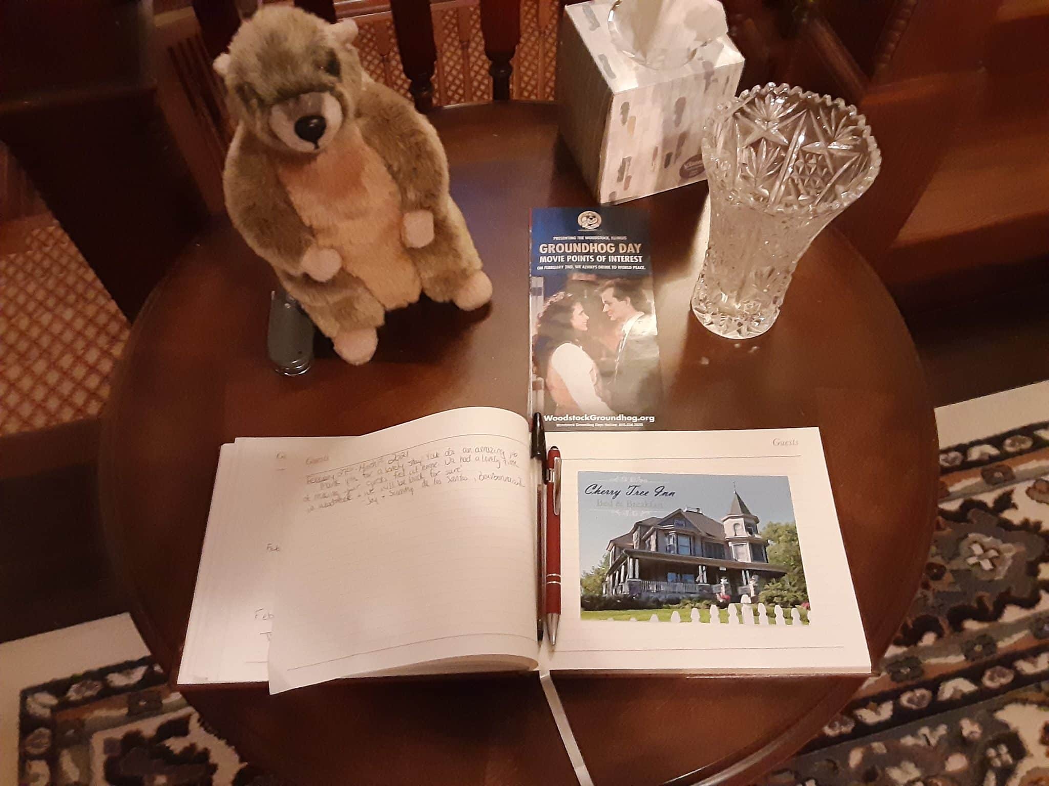 book open on wood table with pen in the binding and stuffed groundhog toy sitting behind it