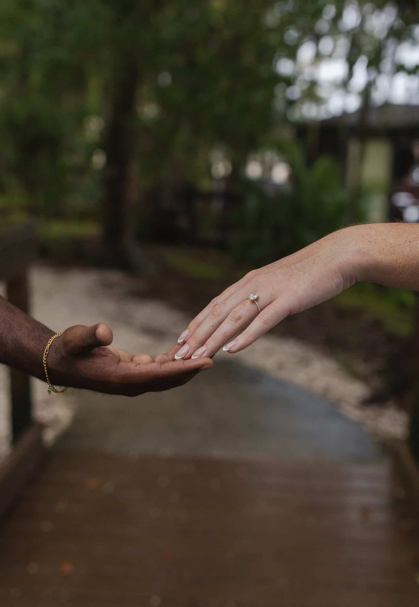 two hands touching fingertips in front of outdoor sidewalk