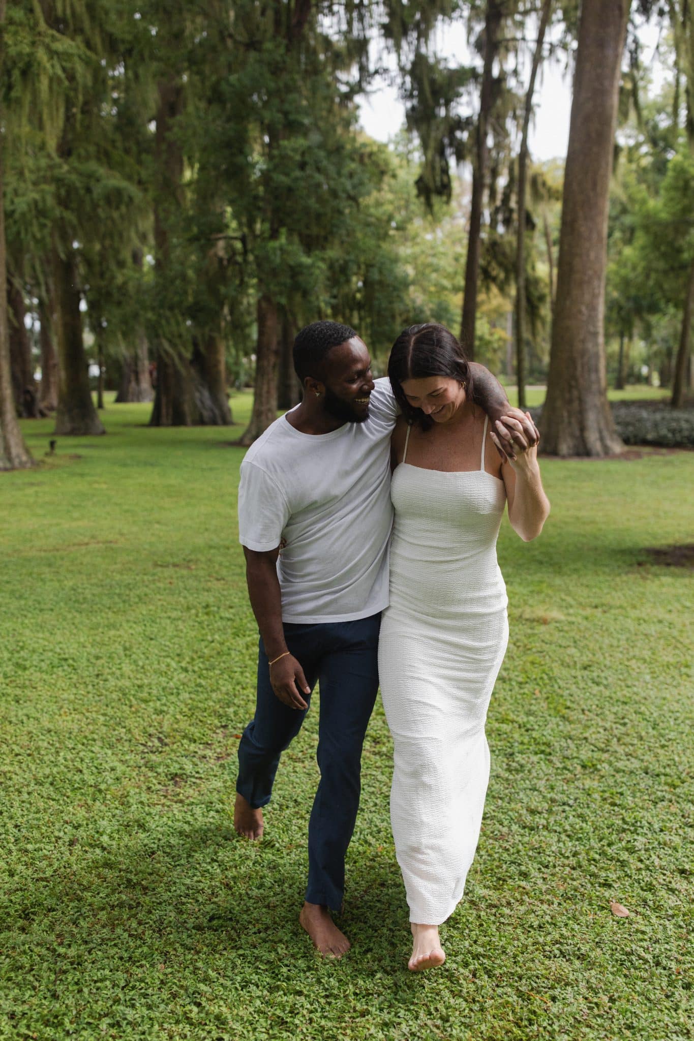 couple walk together outside in grass for pictures