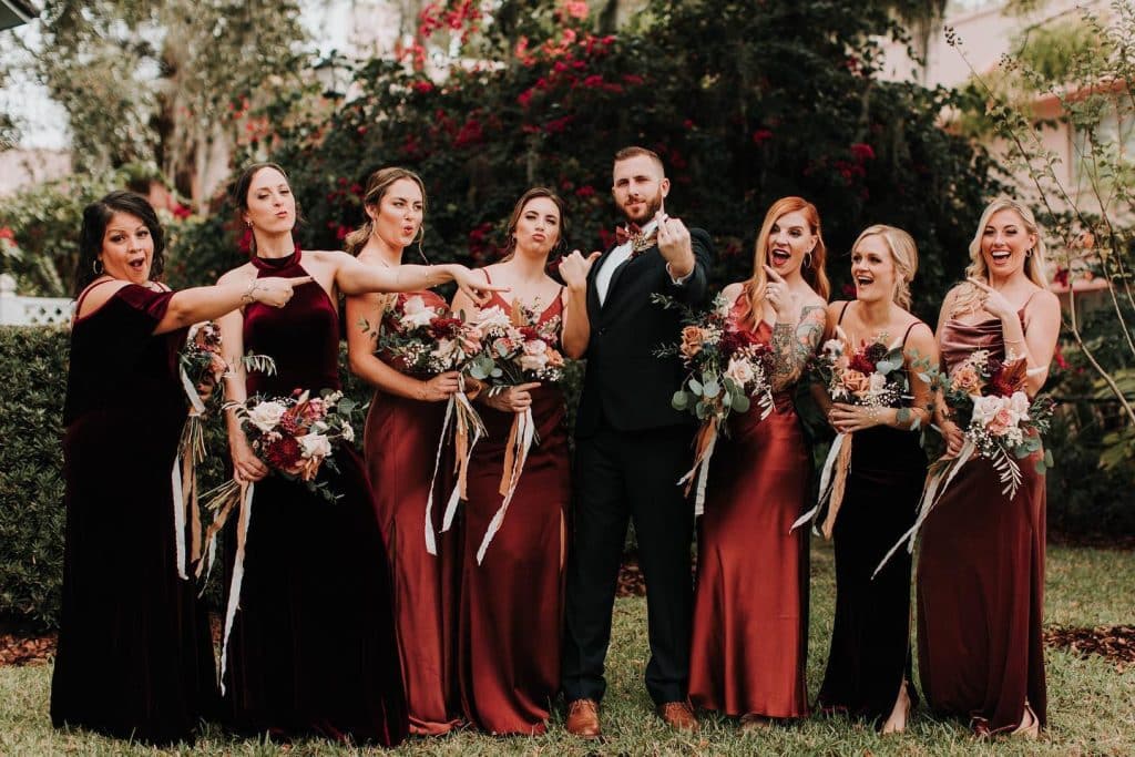 members of the wedding party, women wearing dresses in various shades of red, groom wearing a black suit with a red bowtie, Orlando, FL