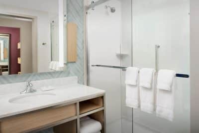 hotel room bathroom, white towels, sink and counter, clear glass shower, mirror, Central, FL