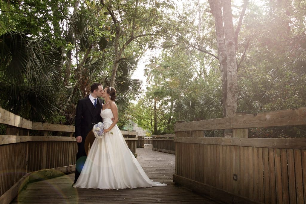 bride and groom kissing on a wooden bridge, surrounded by trees, The Celebration Hotel, Orlando, FL