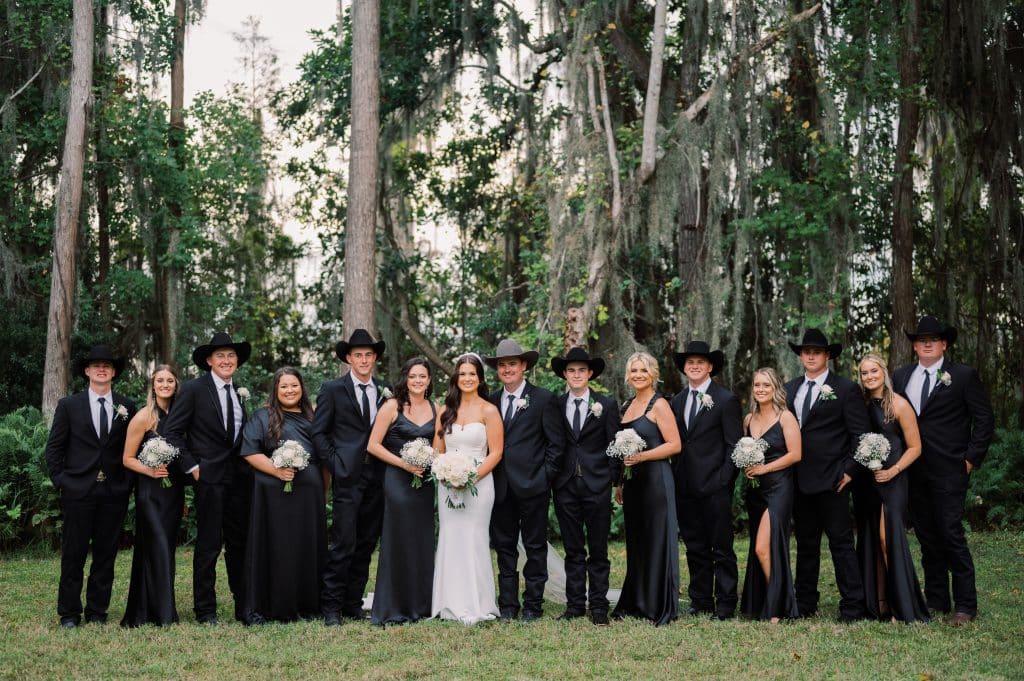 Bride and groom party with the bride in the center. The groomsmen are wearing cowboy hats