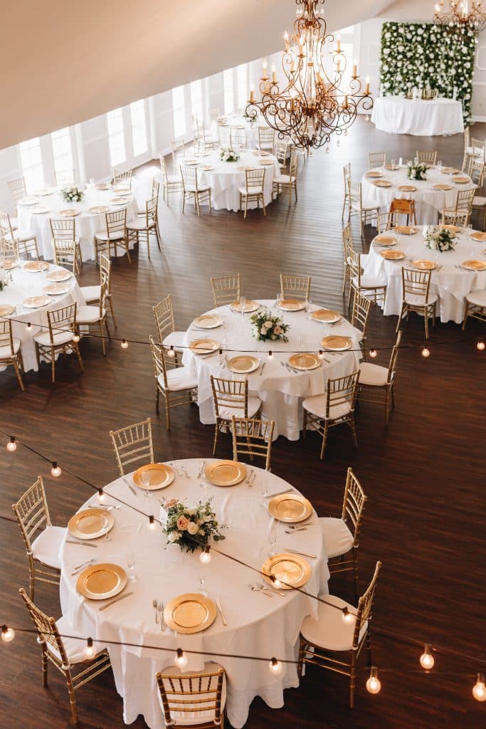 aerial view of the reception set up, round tables, with gold chairs and white cushions, flower centerpieces, wood floors, Tuscawilla Country Club, Orlando, FL