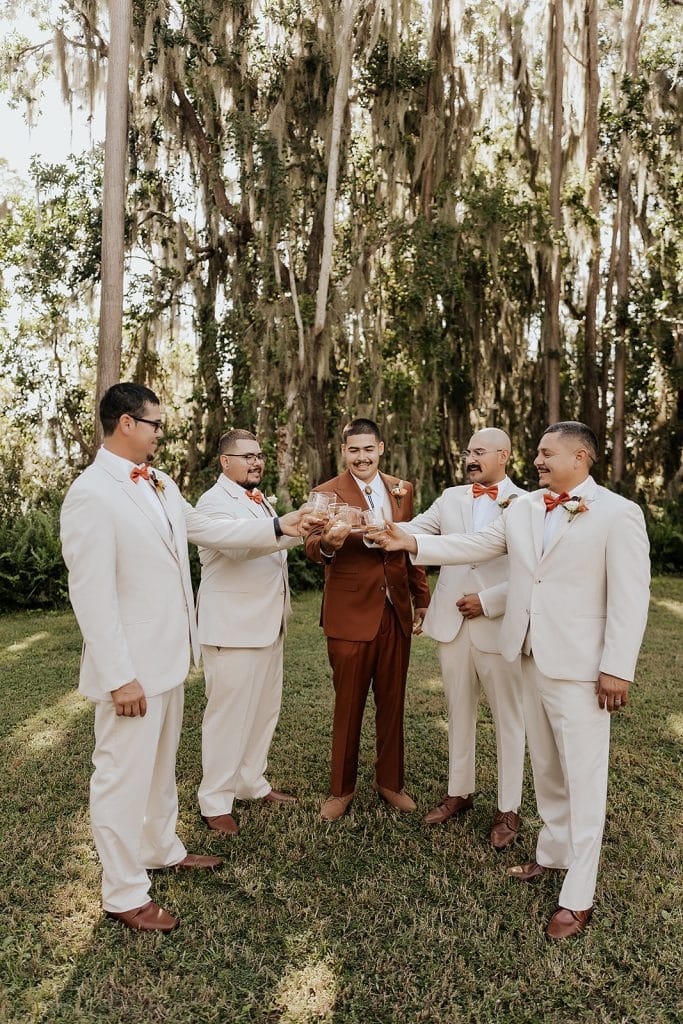 Groom and his groomsmen toasting the wedding. The groom is in autumn colors and his groomsmen are in cream